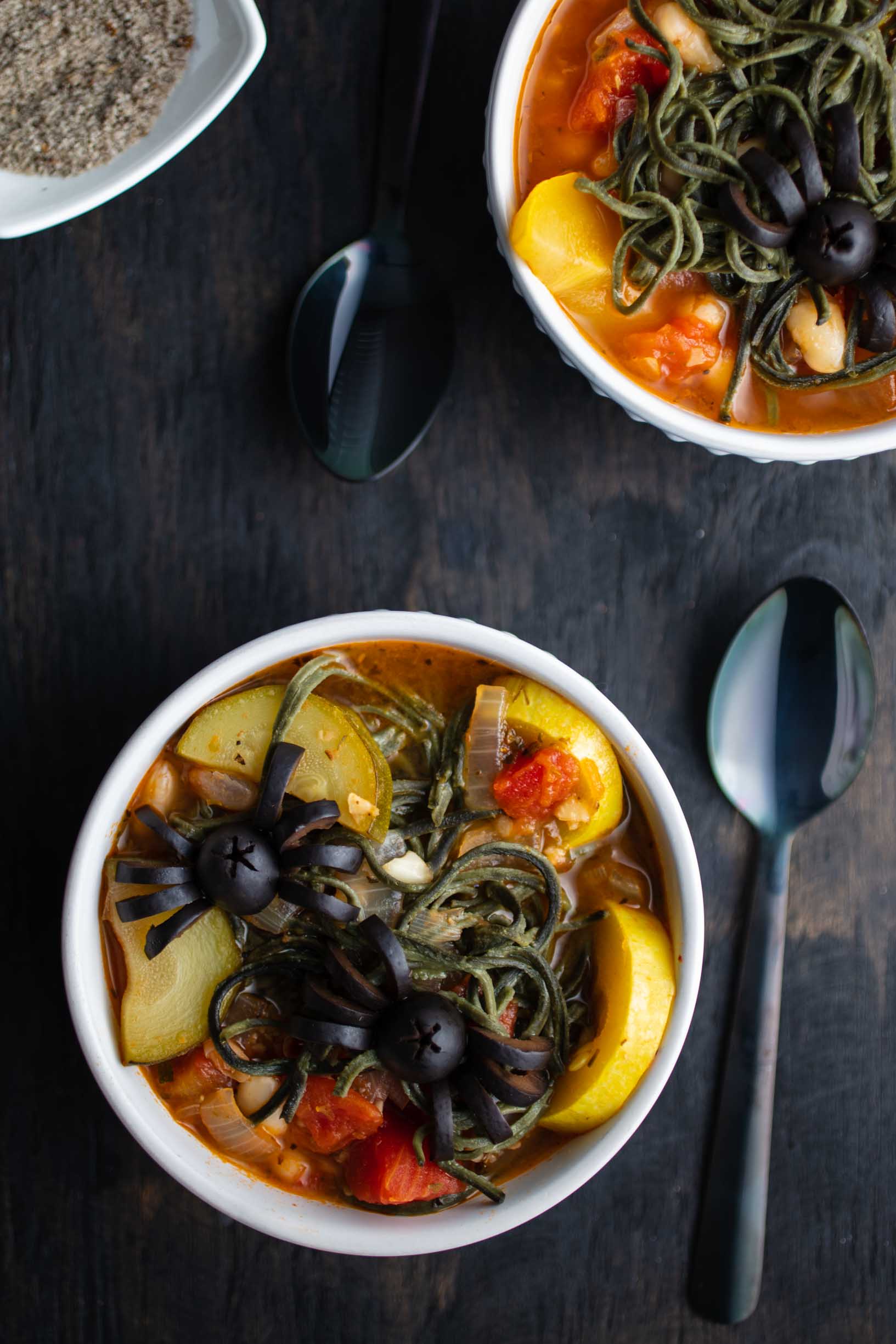 minestrone soup with green noodles and black olive spiders