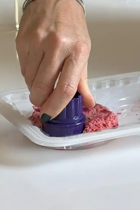 cutting out a baby burger from a normal sized burger pattie.