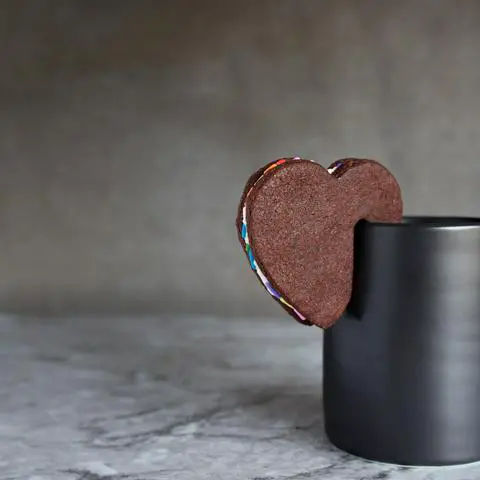 A devil's food cookie sandwich perching on a cup