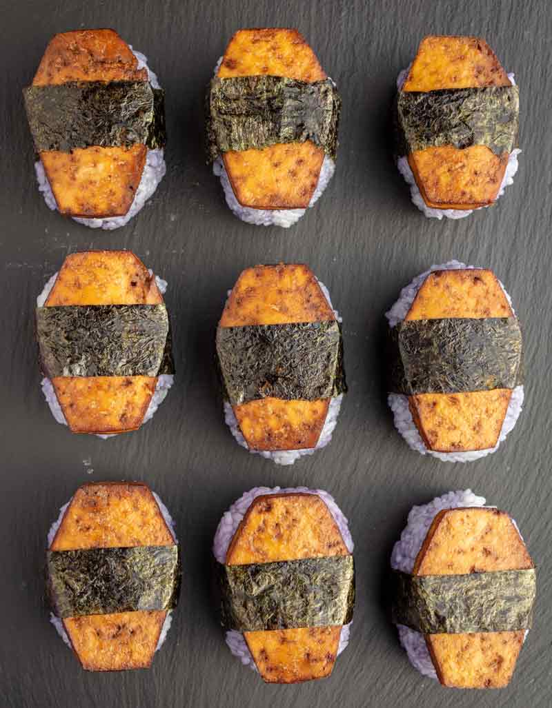 9 vegan spam musubi shaped like coffins on a black slate