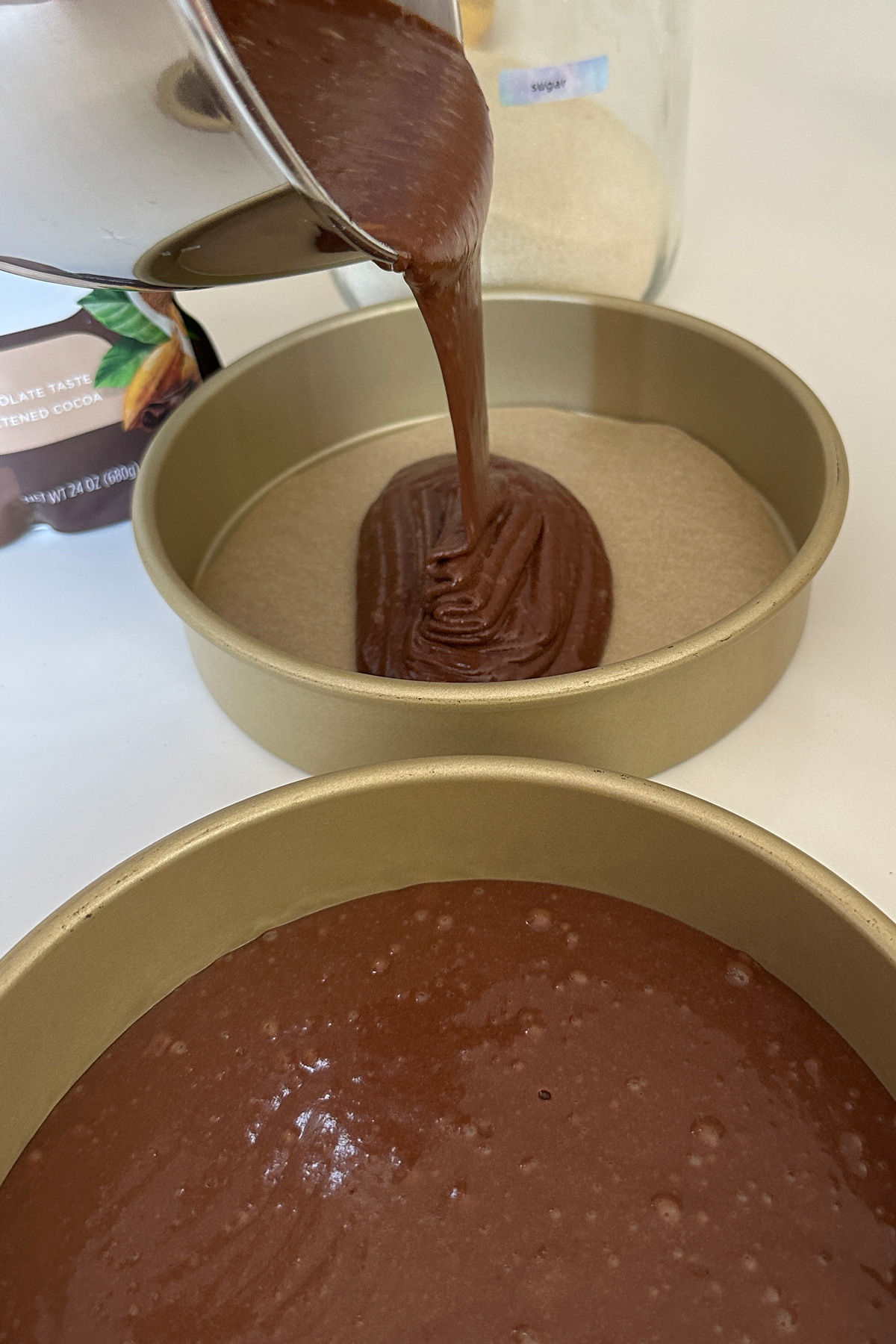 pouring vegan cake batter into cake pans for the nutella cake