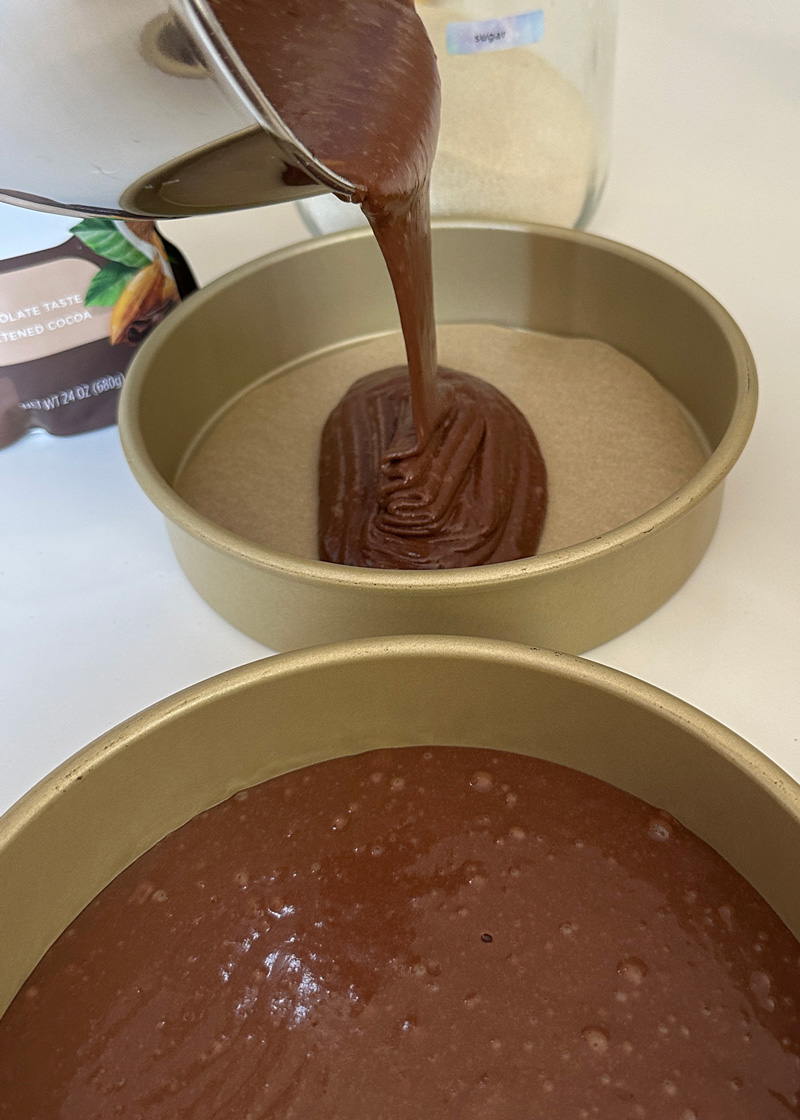 pouring vegan cake batter into cake pans for the nutella cake