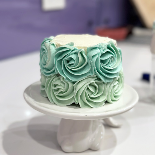piping blue ombre roses onto the mini birthday cake