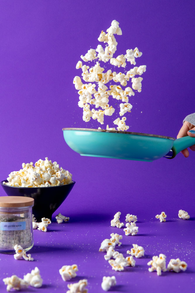 flipping dill pickle popcorn and dill pickle seasoning in a pan