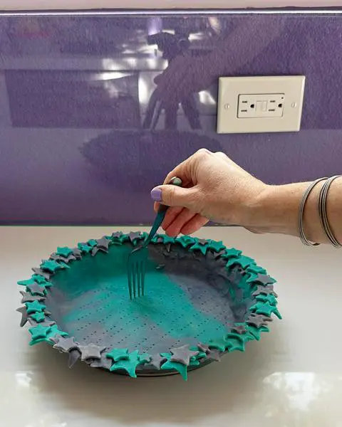 poking holes in the bottom of the pie crust with a fork.