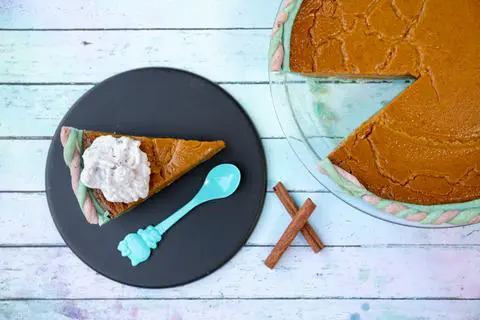 slice of vegan pumpkin pie with blue and purple crust on a plate.