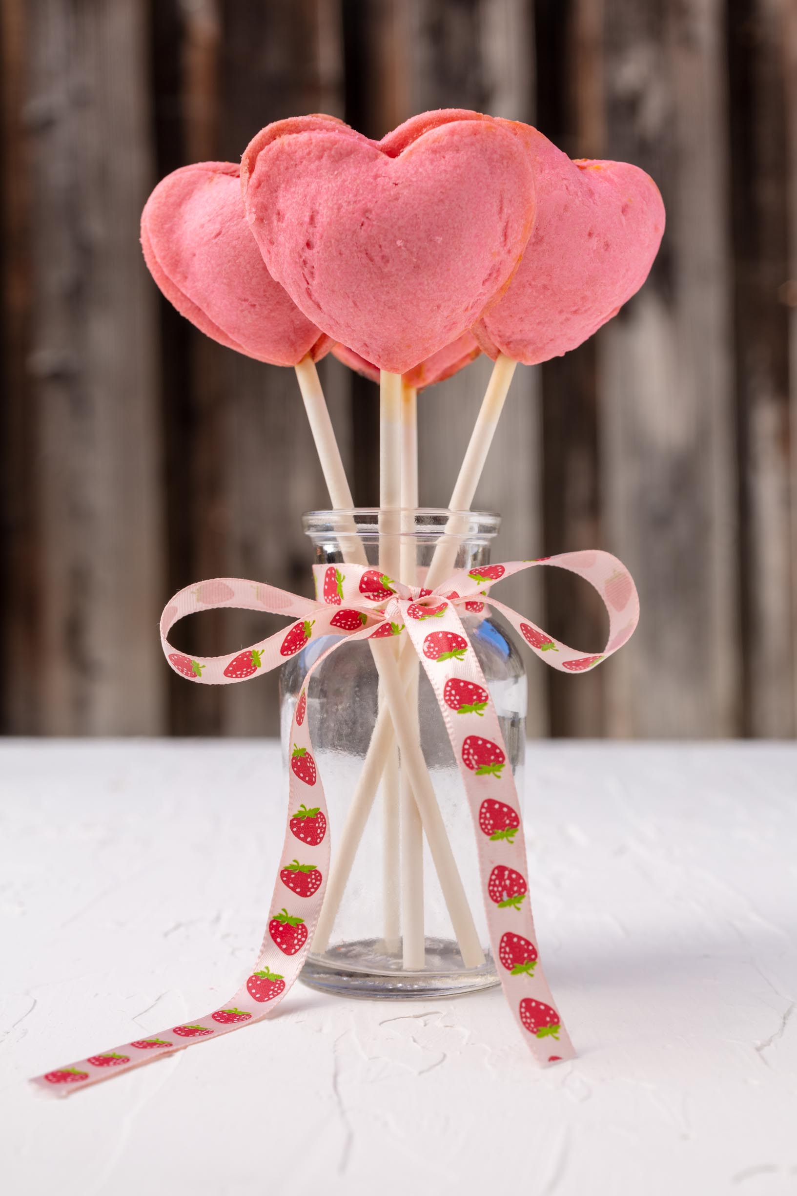 pink heart shaped pie pops sticking out of a jar tied with a bow.