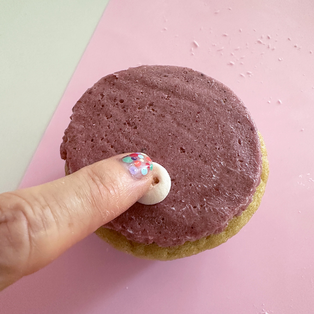 pressing a vegan marshmallow pig snout onto a pink frosted cupcake.