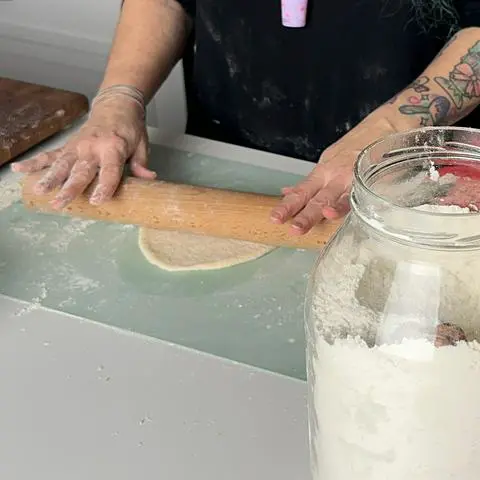 rolling a round piece of pizza dough on a silicone mat.