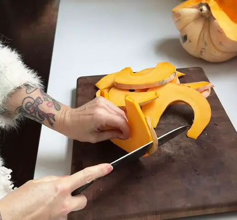 removing the tough pumpkin skin with a knife.