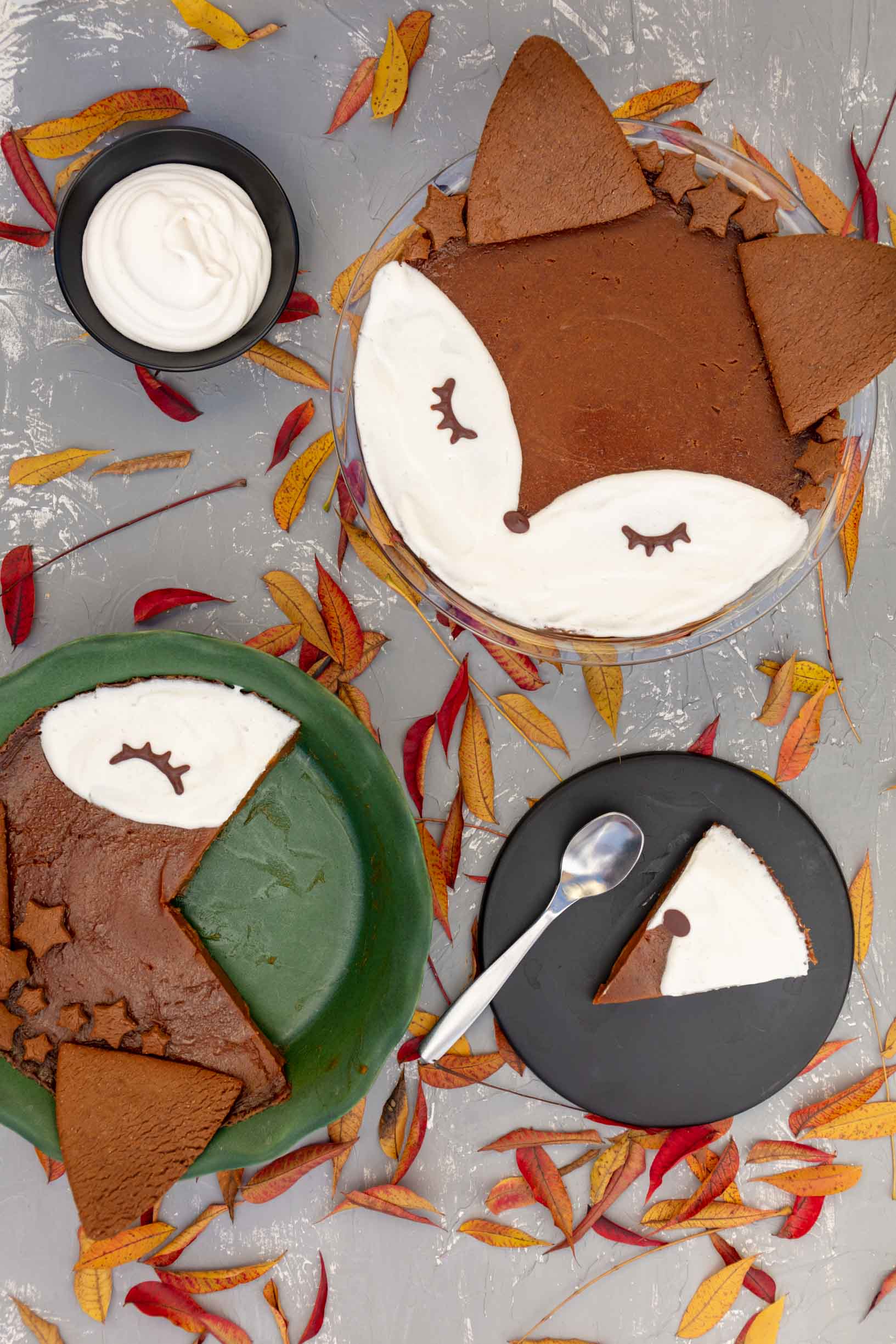 two vegan gluten-free pumpkin pies decorated like foxes with a slice on a plate