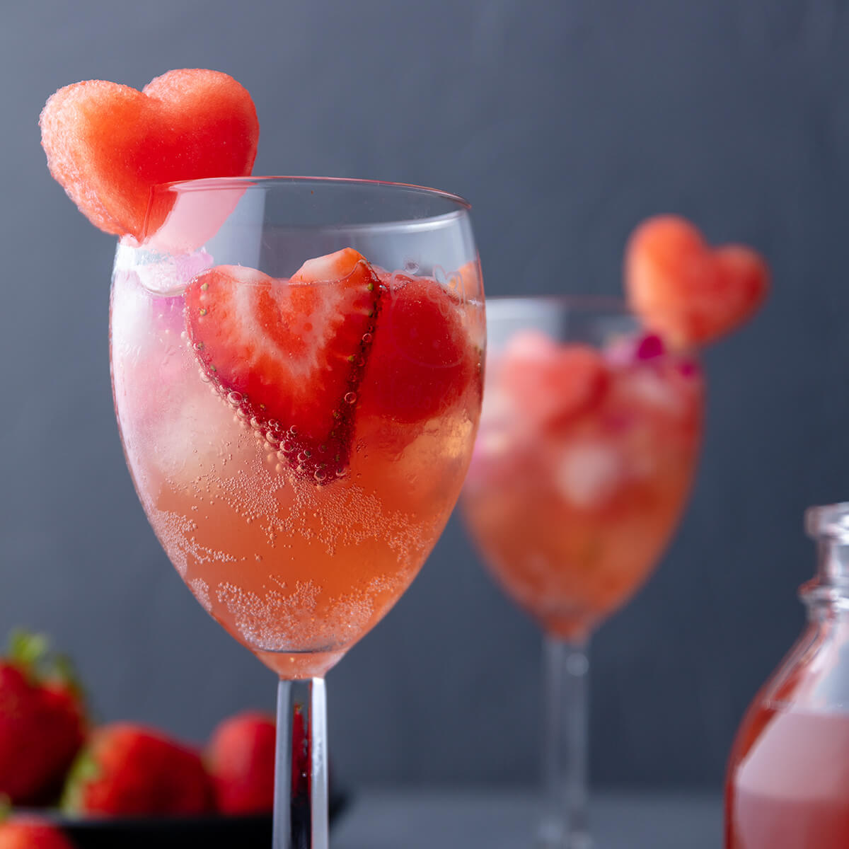 2 glasses of pink sangria with heart shaped watermelon and strawberries in the glasses