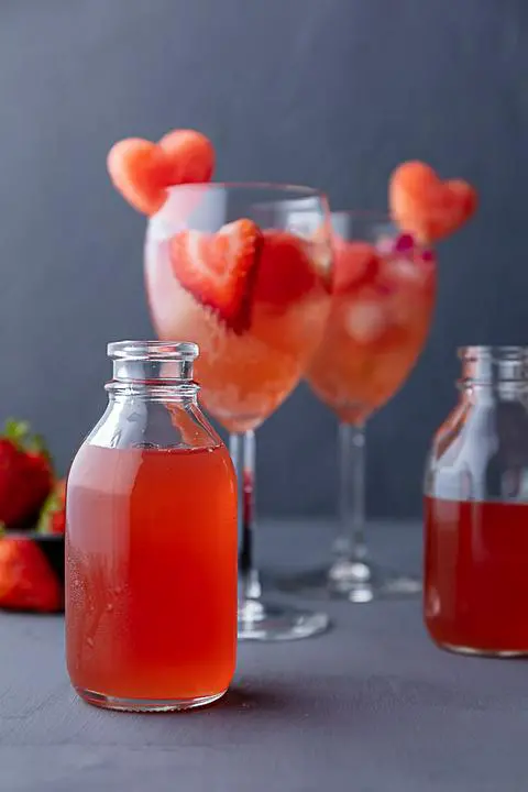 small jar of vegan watermelon syrup with glasses of watermelon sangria in the background