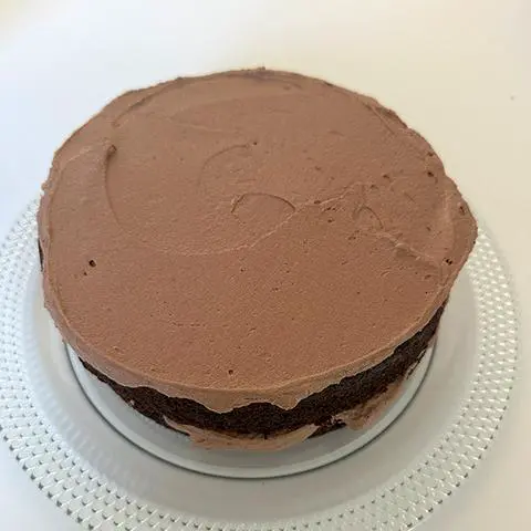 vegan chocolate frosting spread on a round vegan chocolate cake.