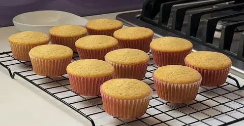 12 vegan vanilla cupcakes on a cooling rack.