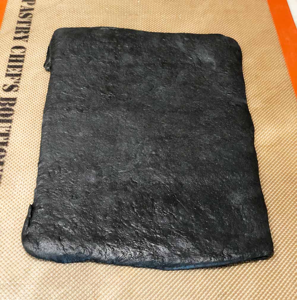 black bread dough rolled out into a rectangle shape