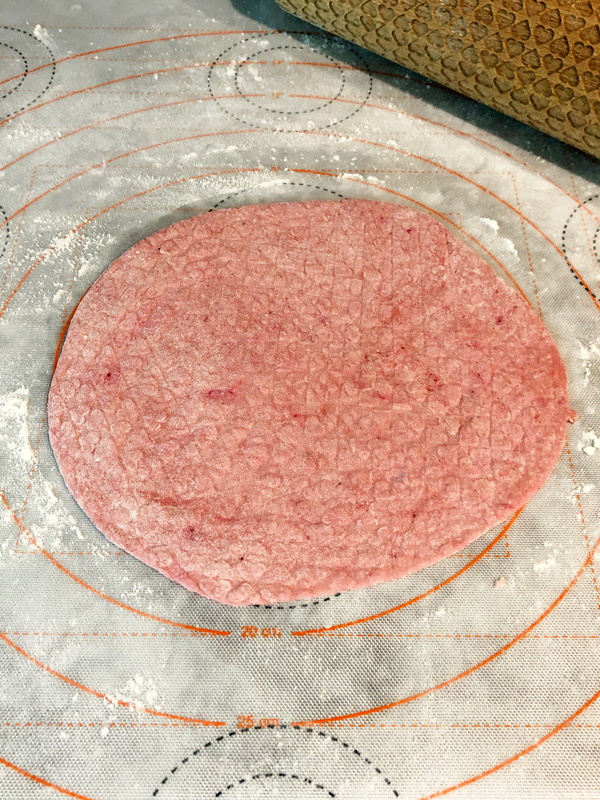 rolling out a pink beetroot-colored tortilla