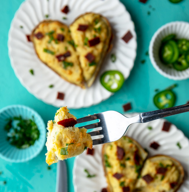 taking a bite from a heart shaped vegan twice baked potato