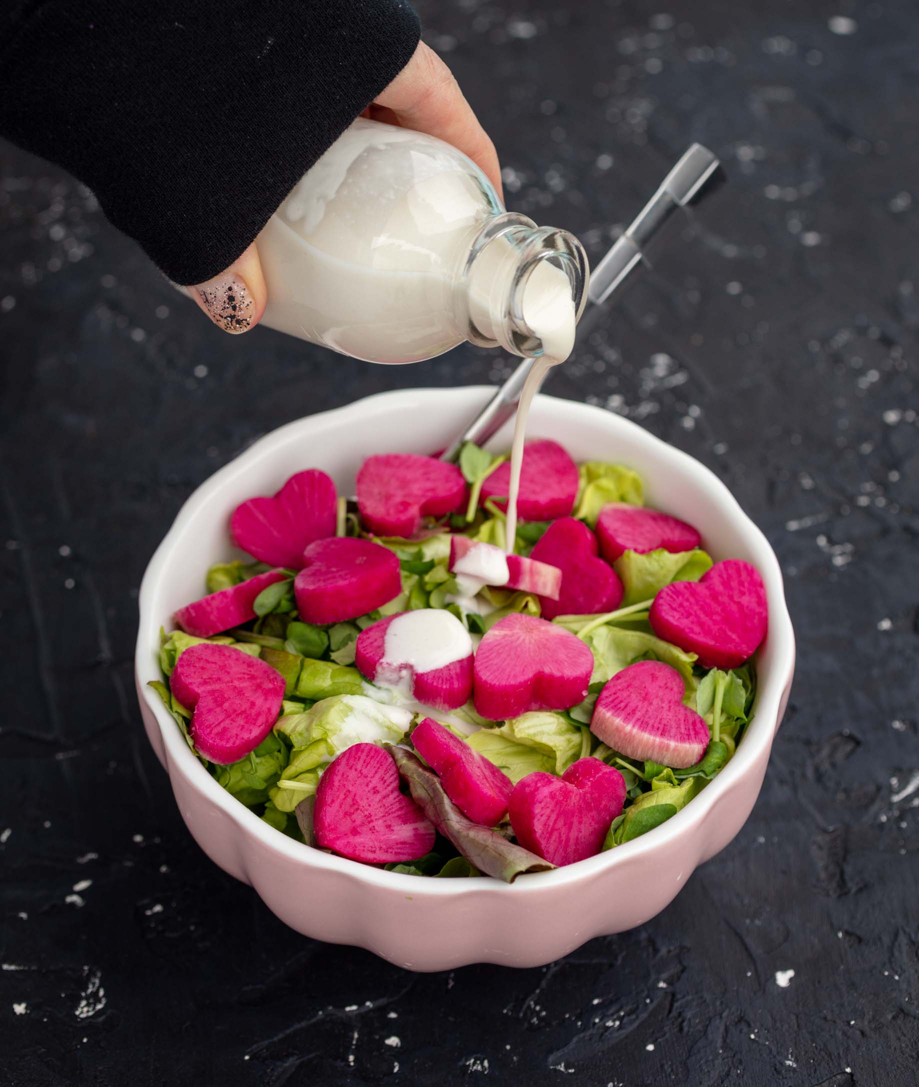 pouring dressing on watermelon radish salad